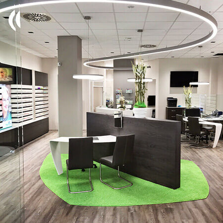 Modern eingerichtetes Optikergeschäft mit Beratungstischen, Regalen und stilvoller Beleuchtung.